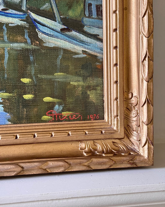 Framed oil on canvas depicting boats on the river Seine in Poissy, near Paris. Attributed to the style of Albert Marquet, a French painter. Signed Axier 1976. An impressionist painting with the use of bright blue and white colours used throughout the landscape, with small trees dotting the shoreline and fluffy clouds in a pale sky above.