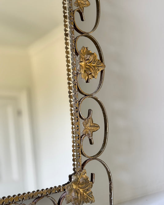 A mid century arched mirror, with a brass metal scroll frame in the shape of flowers, leaves and swirls which give an ultra delicate, feminine finish.