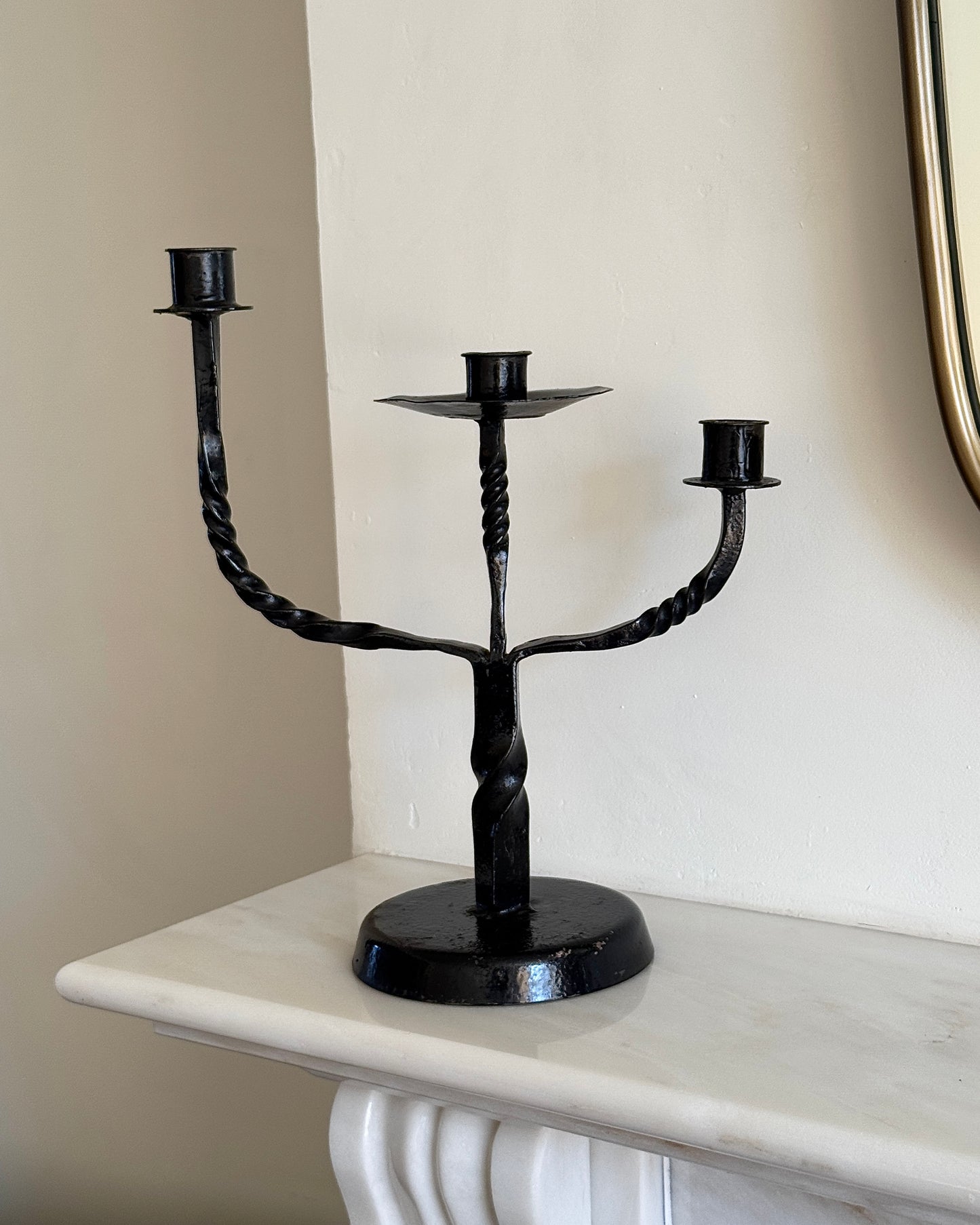 A French mid-century 1950's black brutalist style candelabra with three arms that feature a twisted detail. This twisted detail is seen again near the base. The three arms are at different, graduated height.