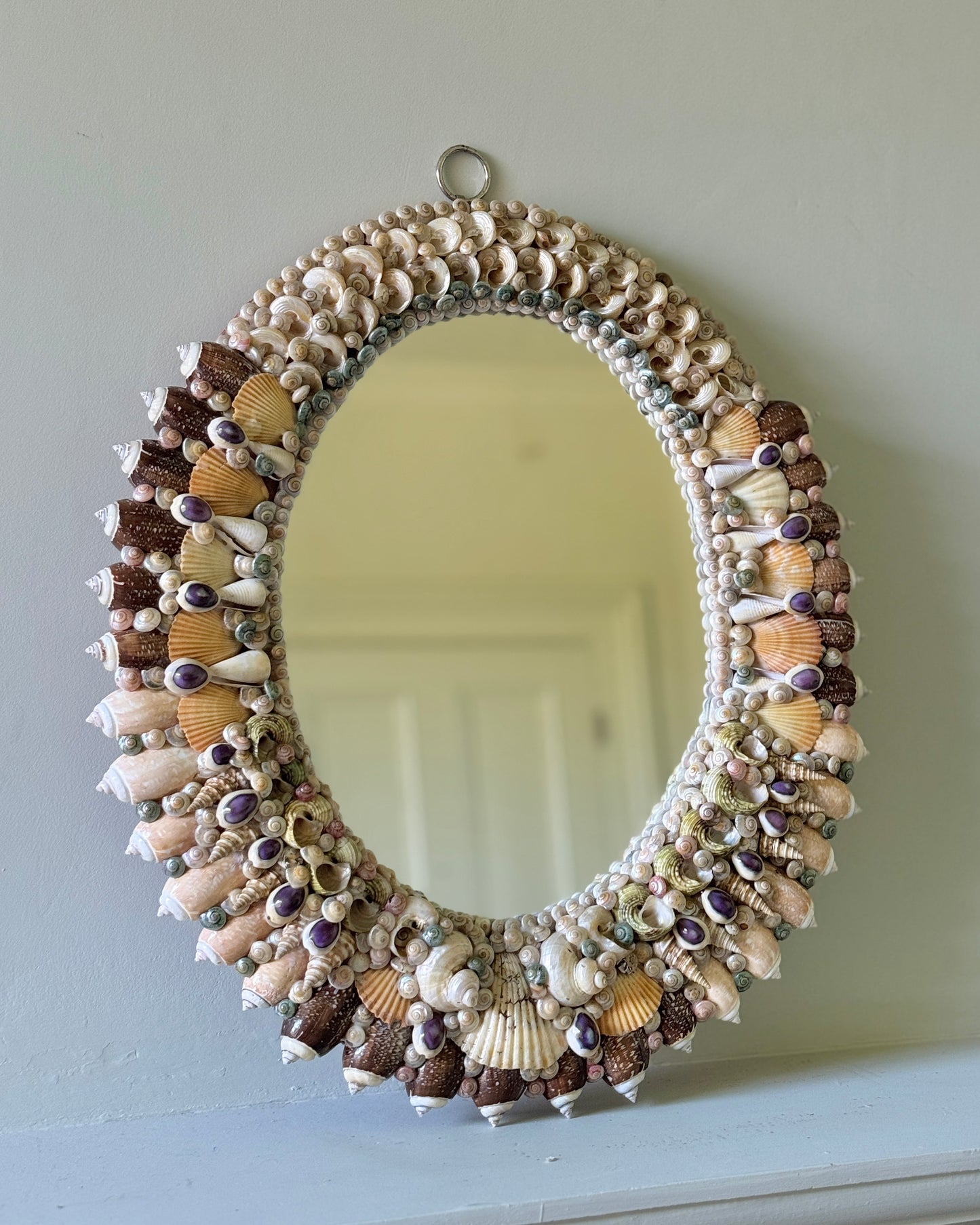 French mid-century shell-encrusted oval mirror against green wall