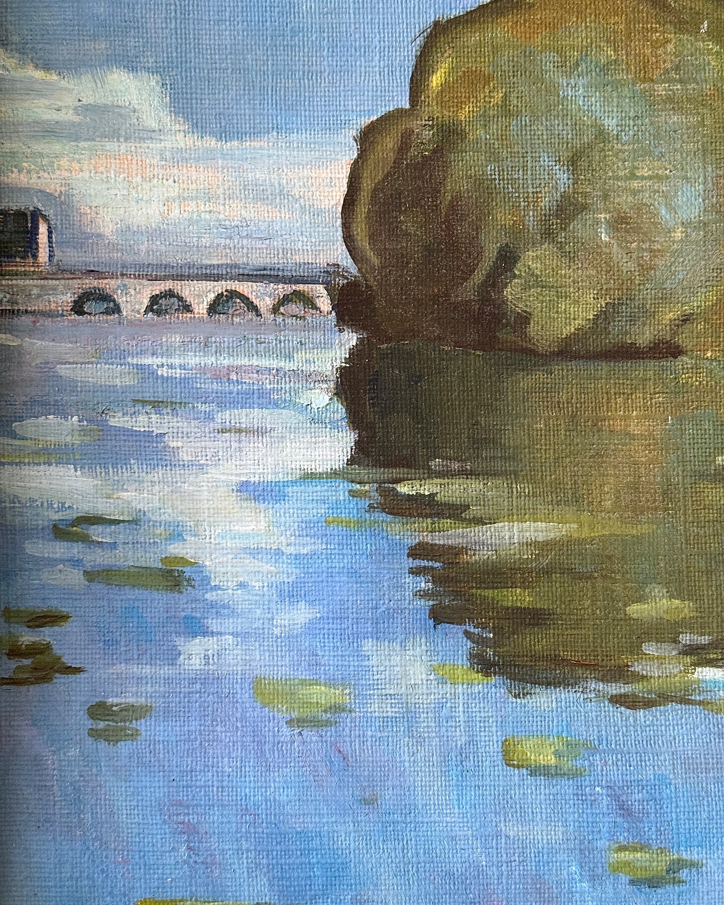 Framed oil on canvas depicting boats on the river Seine in Poissy, near Paris. Attributed to the style of Albert Marquet, a French painter. Signed Axier 1976. An impressionist painting with the use of bright blue and white colours used throughout the landscape, with small trees dotting the shoreline and fluffy clouds in a pale sky above.