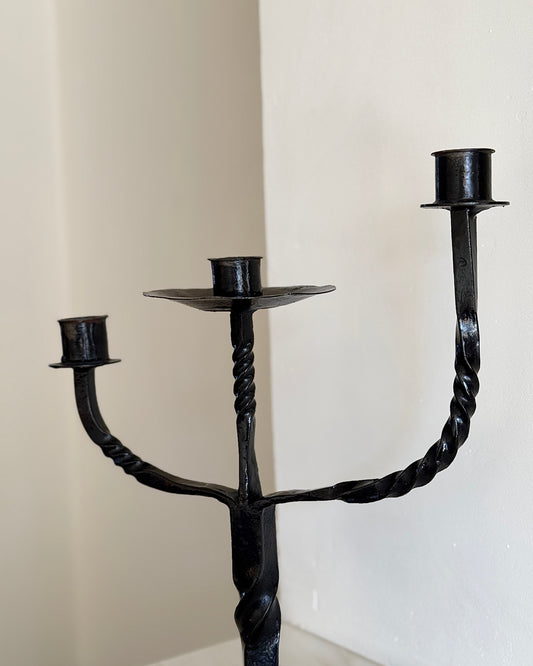 A French mid-century 1950's black brutalist style candelabra with three arms that feature a twisted detail. This twisted detail is seen again near the base. The three arms are at different, graduated height.